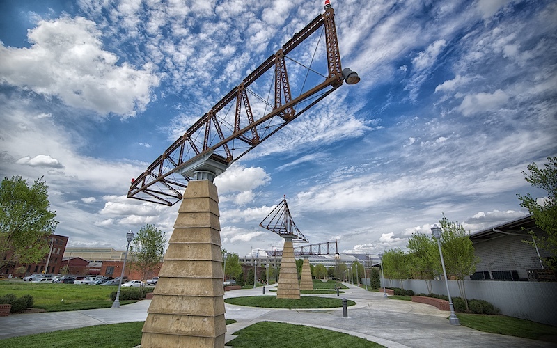 View of 3 large iron sculptures on top of concrete plinths in a row