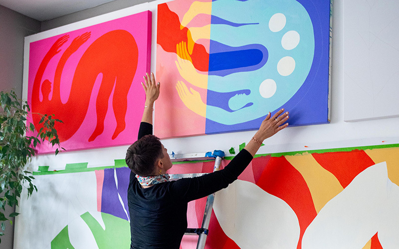 An artist positioning her painting